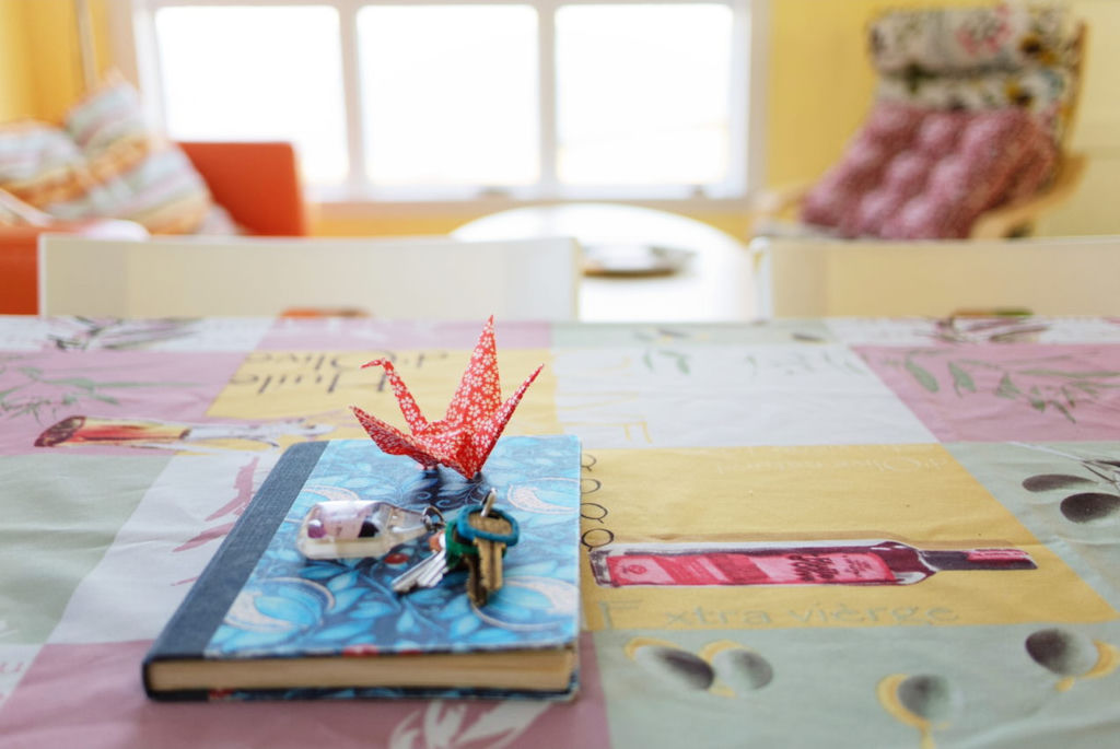 A notebook on a table with keys and an origami crane on it.
