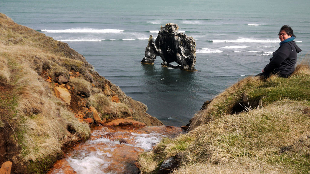 Me sitting on a sea cliff with a sea stack in the background.