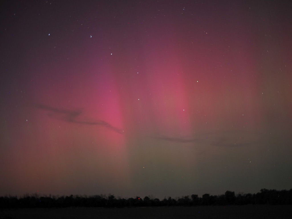 A photo of the northern lights in red and green with the Big Dipper as a guest star.