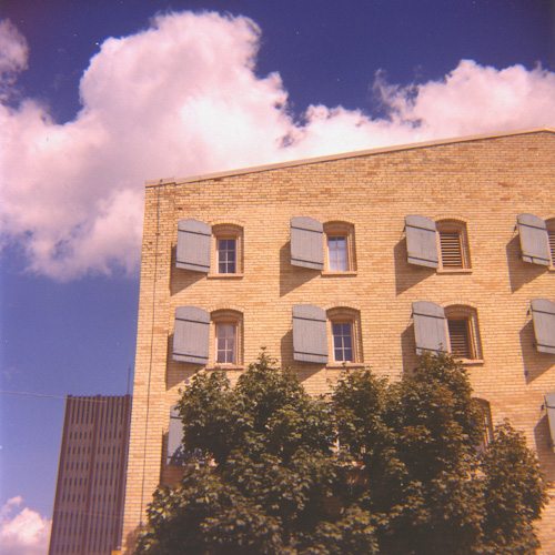 A yellow brick building with light blue window shutters.