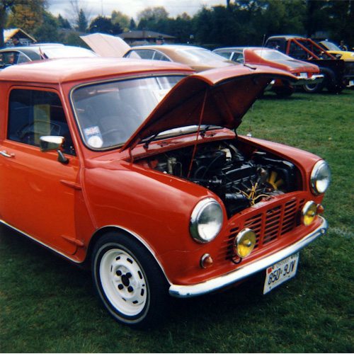A small, old, red car with its hood up. 